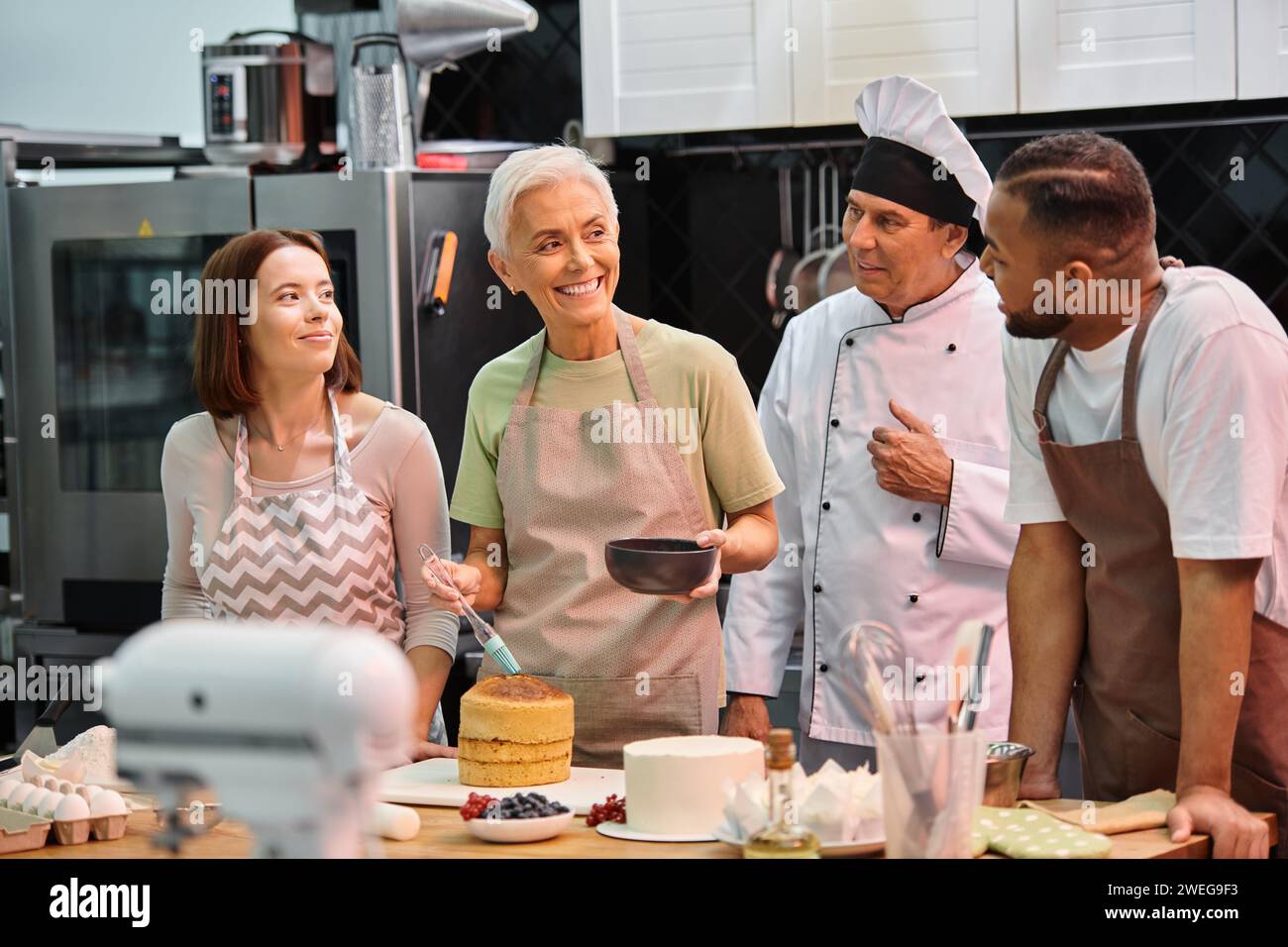 joyeuse femme mature avec brosse en silicone souriant à ses amis divers et chef en chapeau blanc Banque D'Images