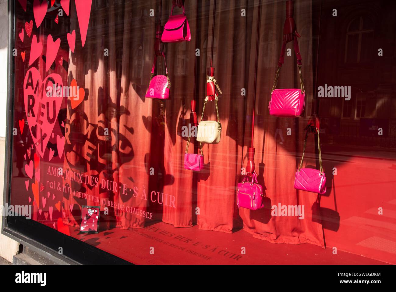 Paris, France - 21 février 2023 : Décoration rouge Saint-Valentin avec des coeurs comme arrière-plan pour les sacs à main fantaisie exposés dans la vitrine du grand magasin BHV. Banque D'Images