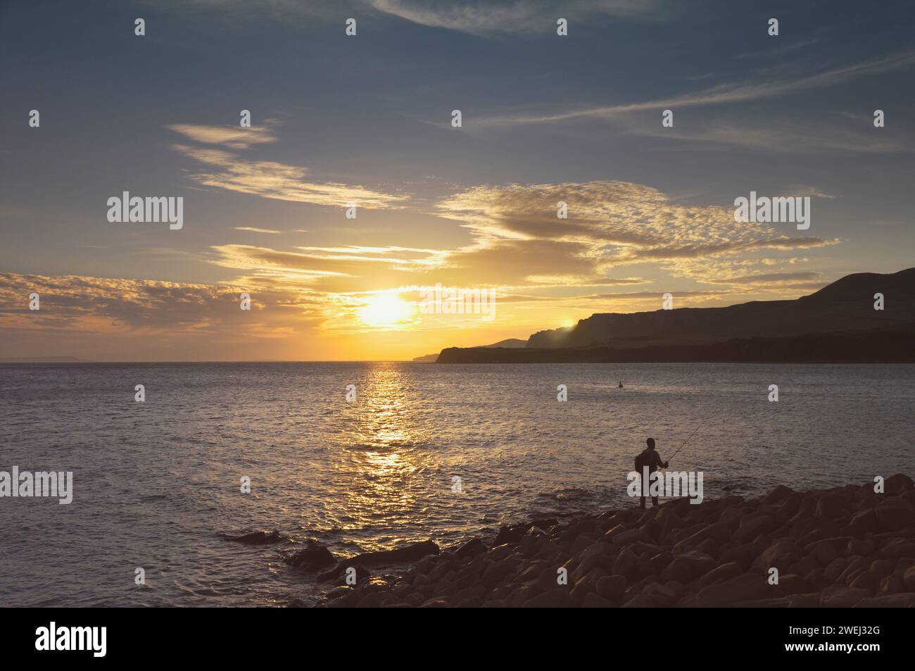 Homme pêchant au coucher du soleil, Kimmeridge Bay, île de Purbeck, site du patrimoine mondial de la côte jurassique, Dorset, Angleterre, Royaume-Uni Banque D'Images