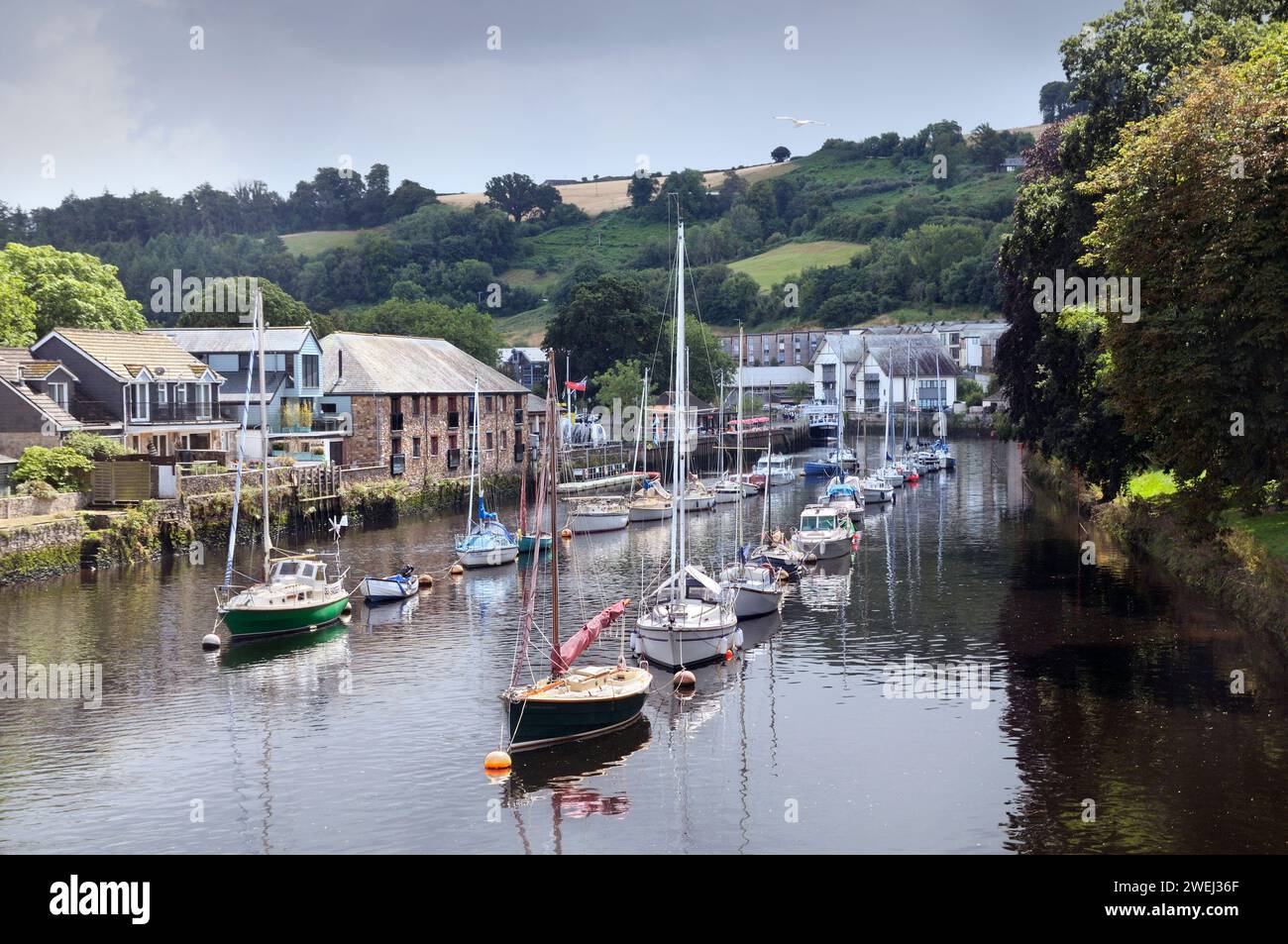 Le soleil brise à travers les nuages gris illuminant les bateaux amarrés sur la rivière Dart à côté de Vire Island, Totnes, South Hams, South Devon, Angleterre, ROYAUME-UNI Banque D'Images