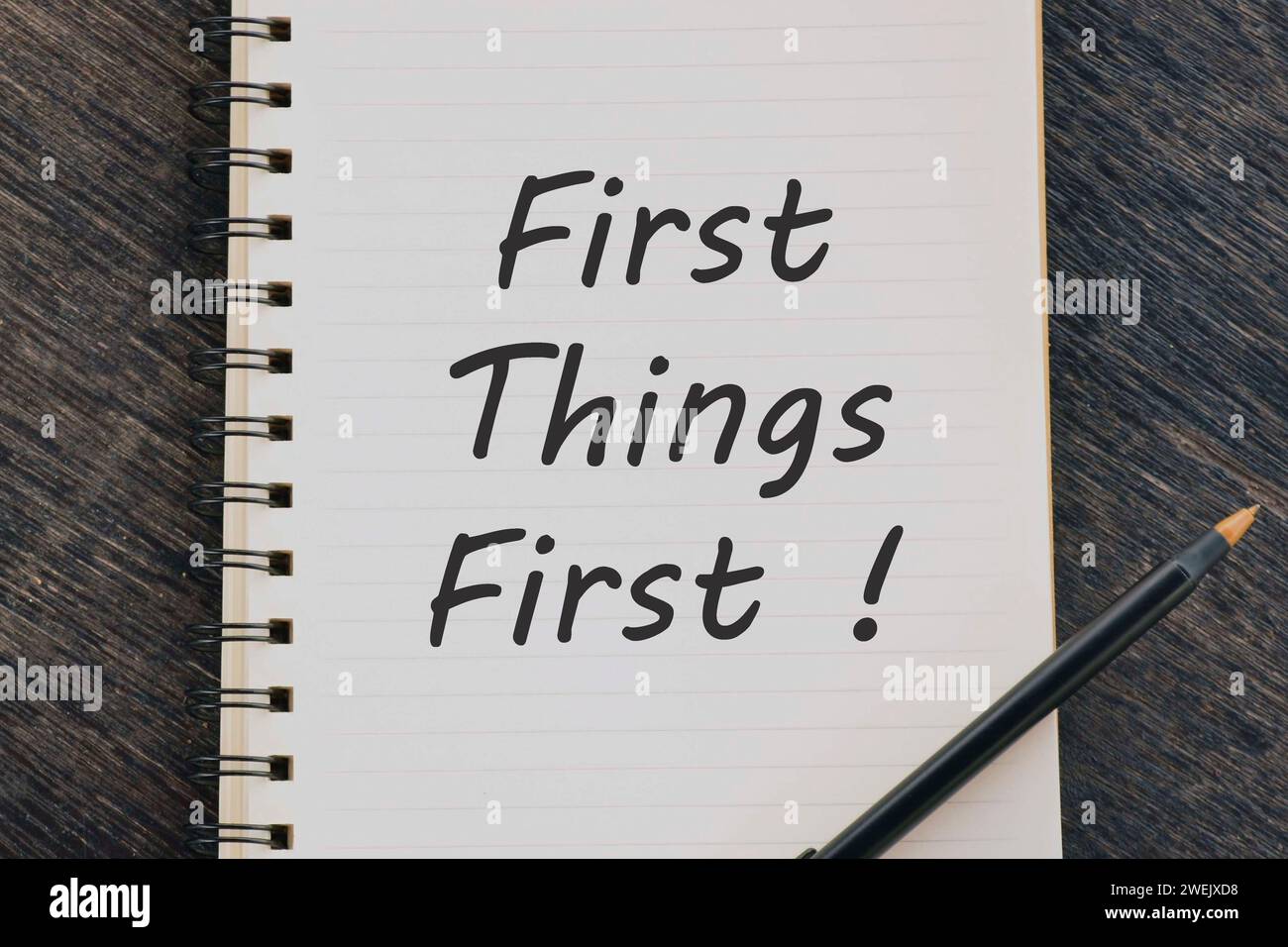 Premières choses Premier texte sur bloc-notes avec stylo sur bureau en bois. Banque D'Images