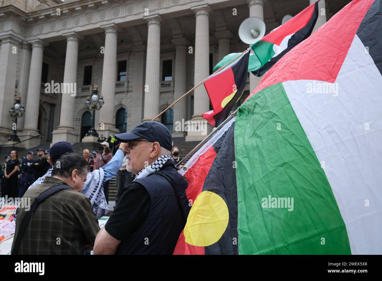 Manifestant avec un grand drapeau palestinien sur les marches du Parlement Melbourne Australie 2024 Banque D'Images