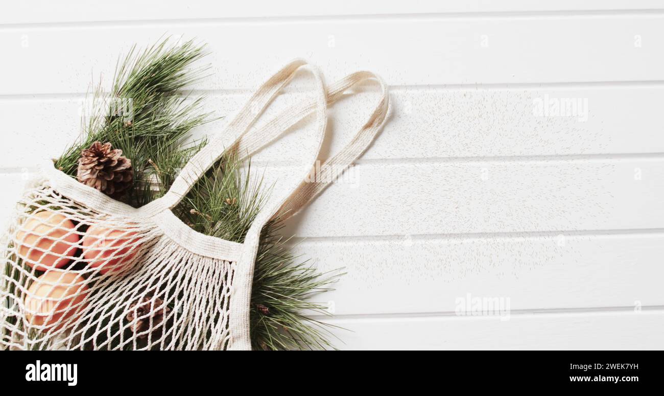 Frohe weihnachten texte en rouge sur sac à provisions avec bracnhes de noël sur fond de bois blanc Banque D'Images