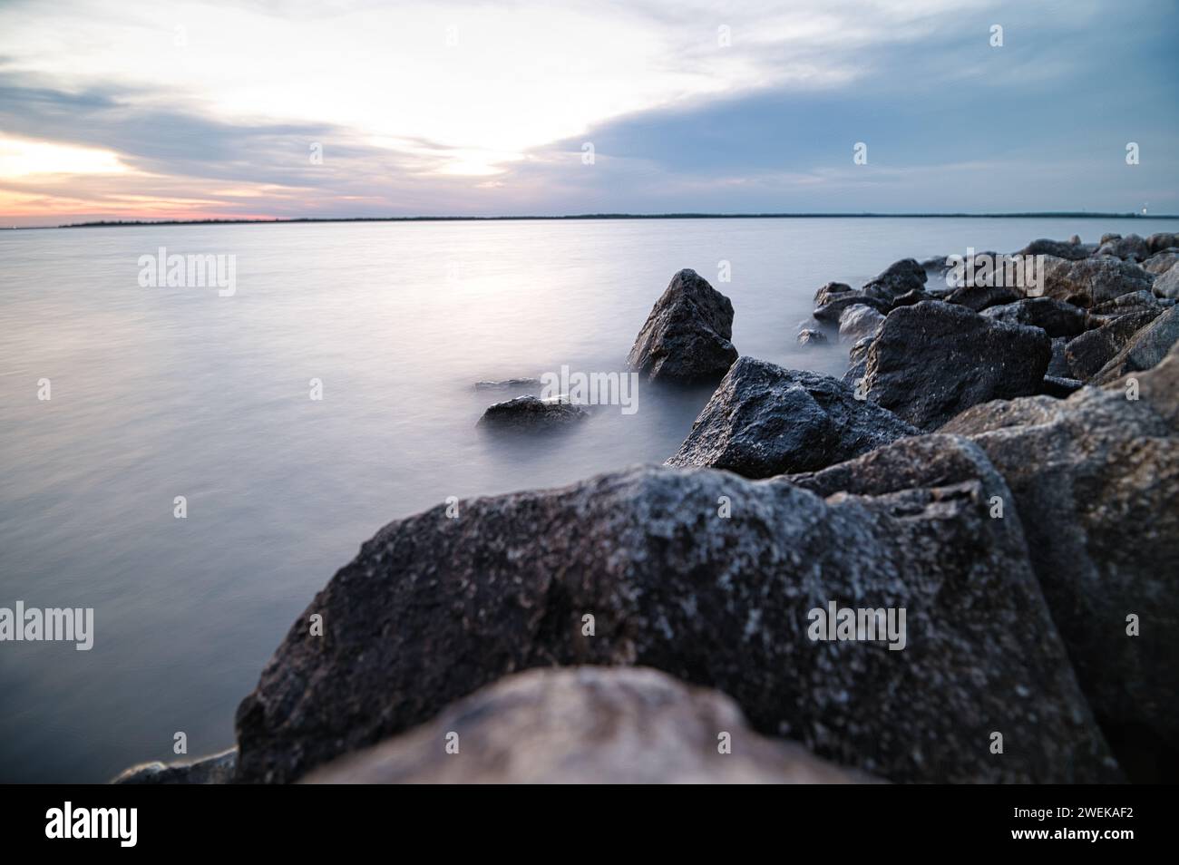 Affleurement rocheux près de l'eau avec ciel illuminé Banque D'Images