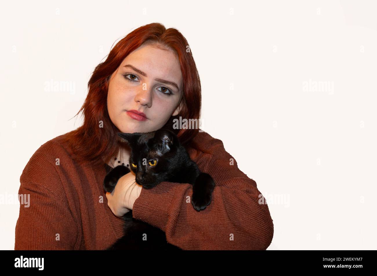 Une fille avec son chat noir et fond blanc Banque D'Images