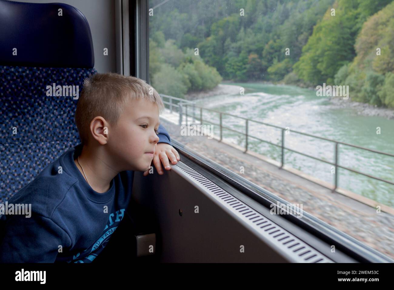 Un petit garçon regarde soigneusement au loin à travers la fenêtre du train Banque D'Images