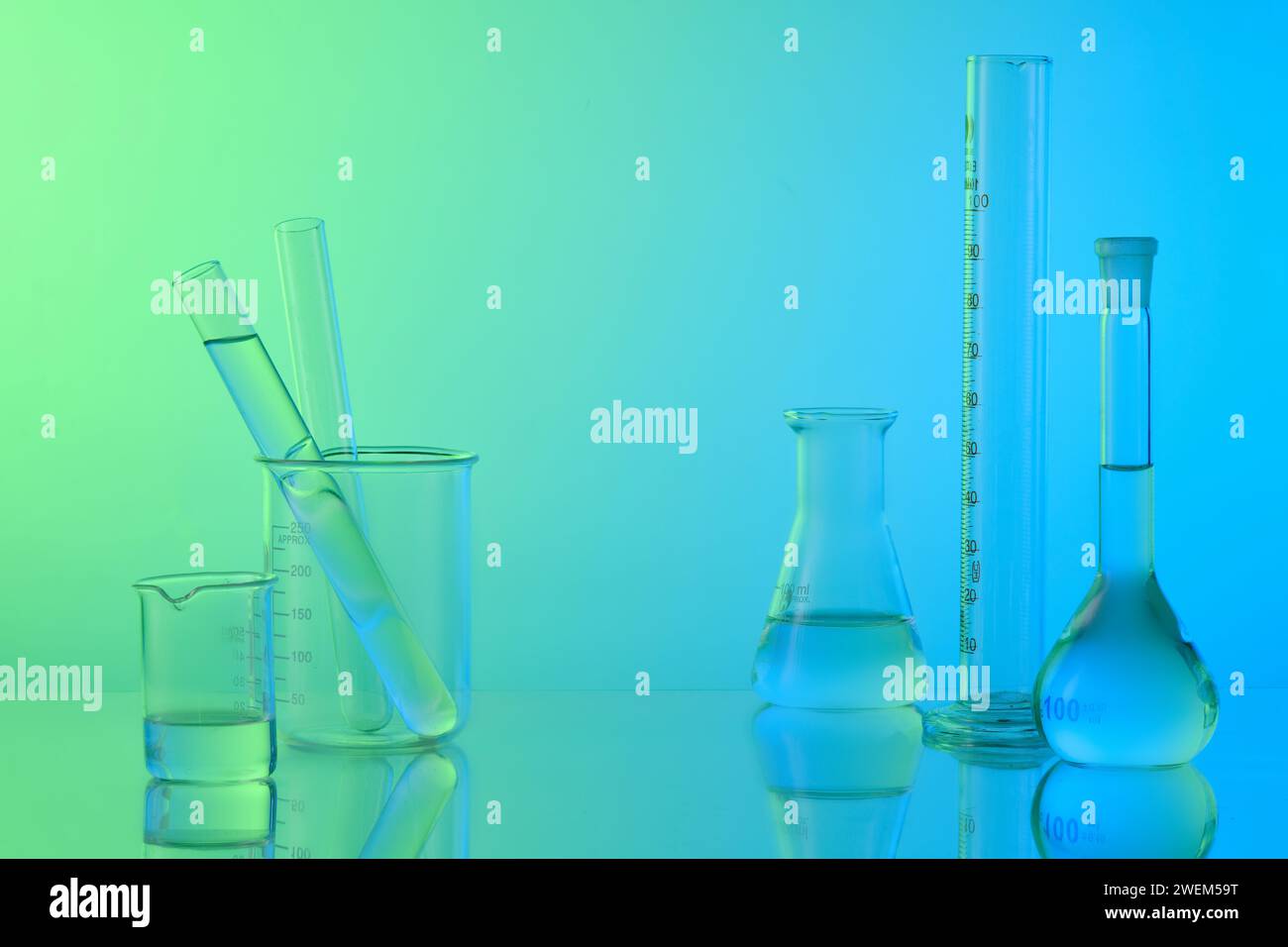 Concept de laboratoire avec verrerie de laboratoire - flacon erlenmeyer, tubes à essai et bécher rempli de liquide incolore sur fond de gradient. Espace pour affichage prod Banque D'Images