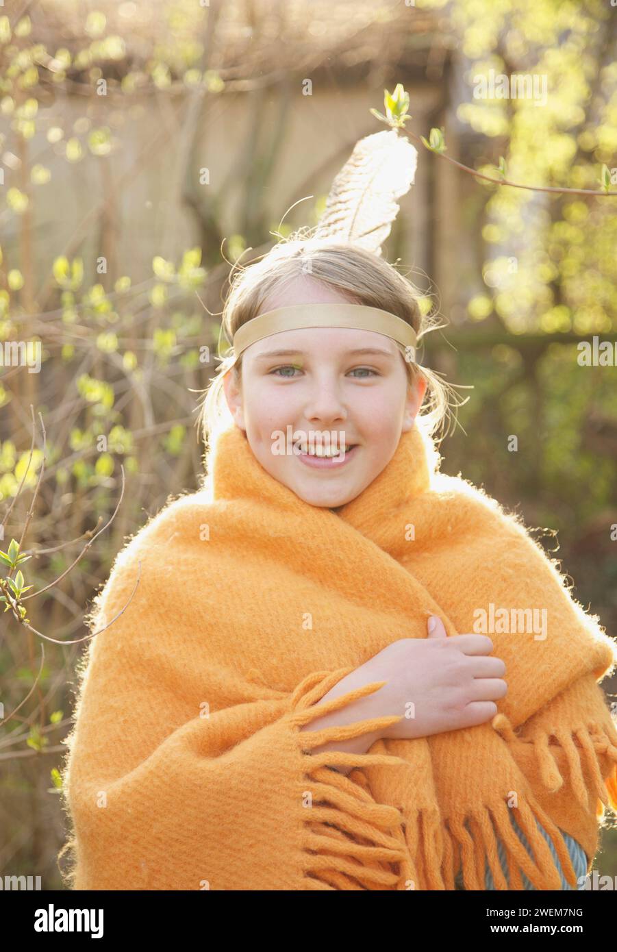 Fille enveloppée dans une couverture portant une coiffe en plumes indiennes Banque D'Images