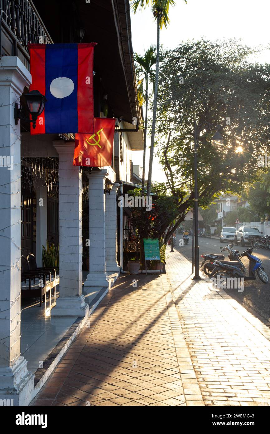 Bâtiment avec drapeau laotien et communiste, pendant l'heure d'or Banque D'Images