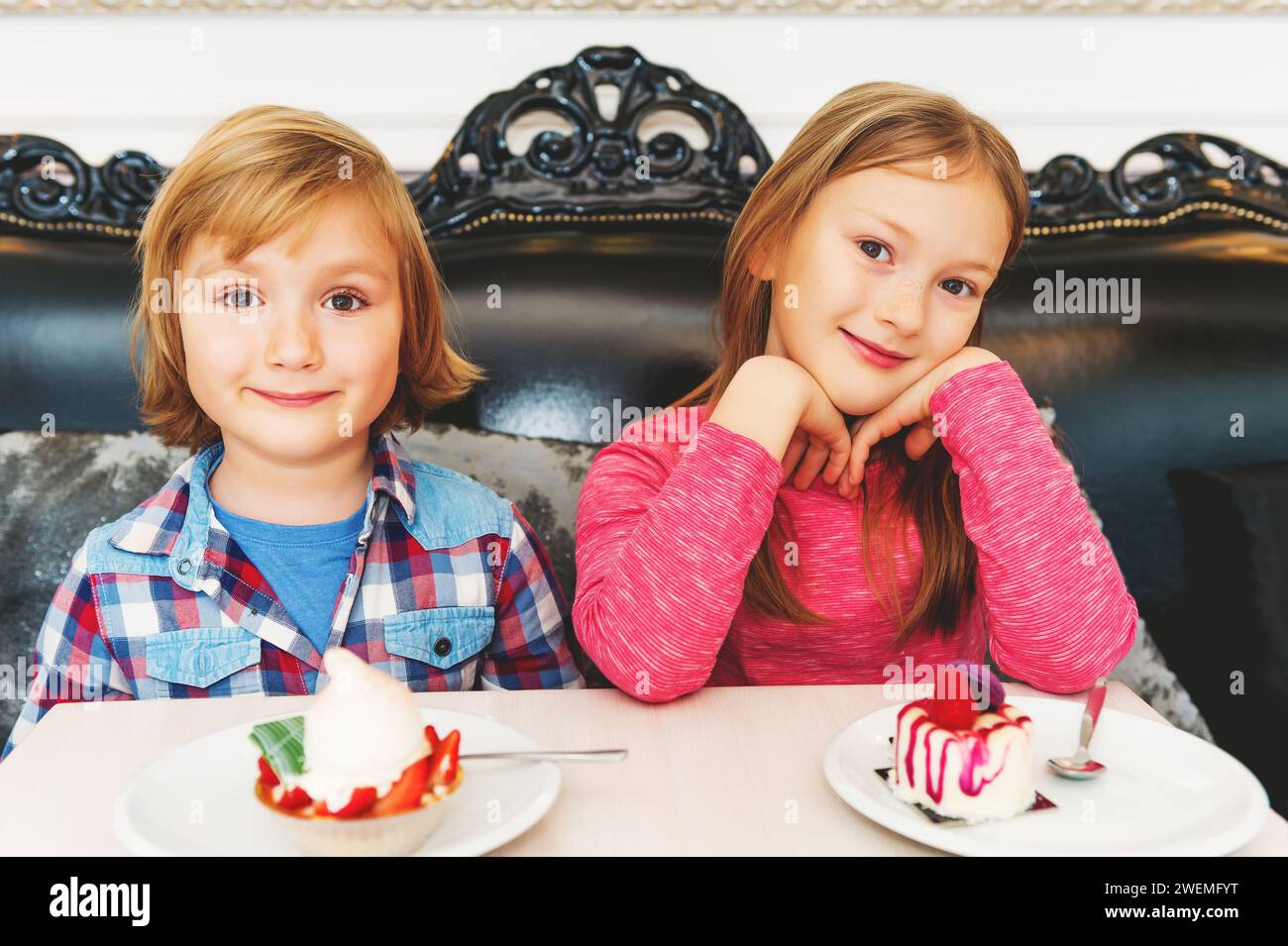 Adorables enfants mangeant des gâteaux dans le café Banque D'Images