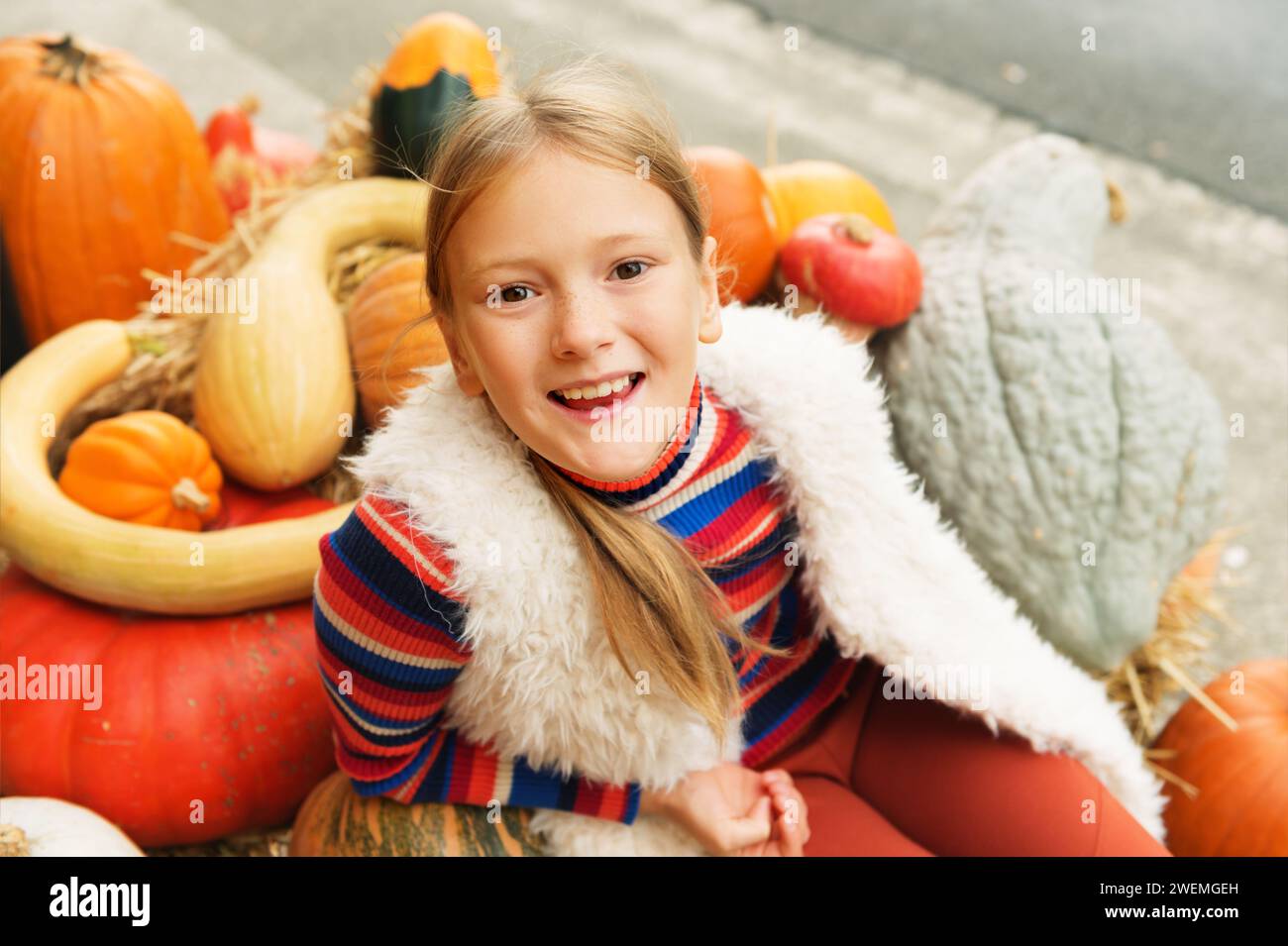 Adorable petite fille de 8-9 ans choisissant la citrouille d'halloween sur le marché de la ferme, s'amuser avec différents types de citrouilles inhabituels Banque D'Images