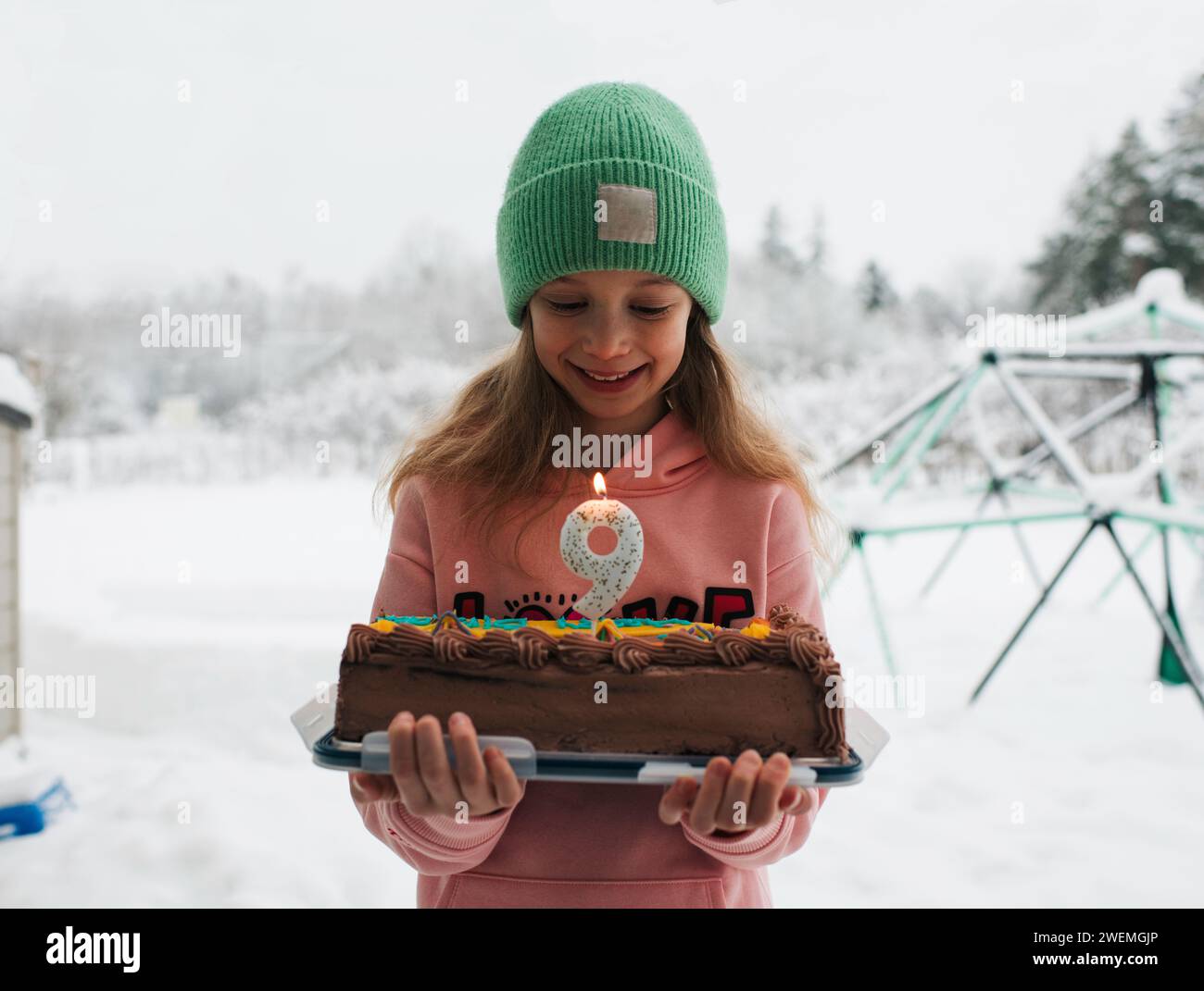 fille de 9 ans regardant son gâteau d'anniversaire avec une bougie Banque D'Images