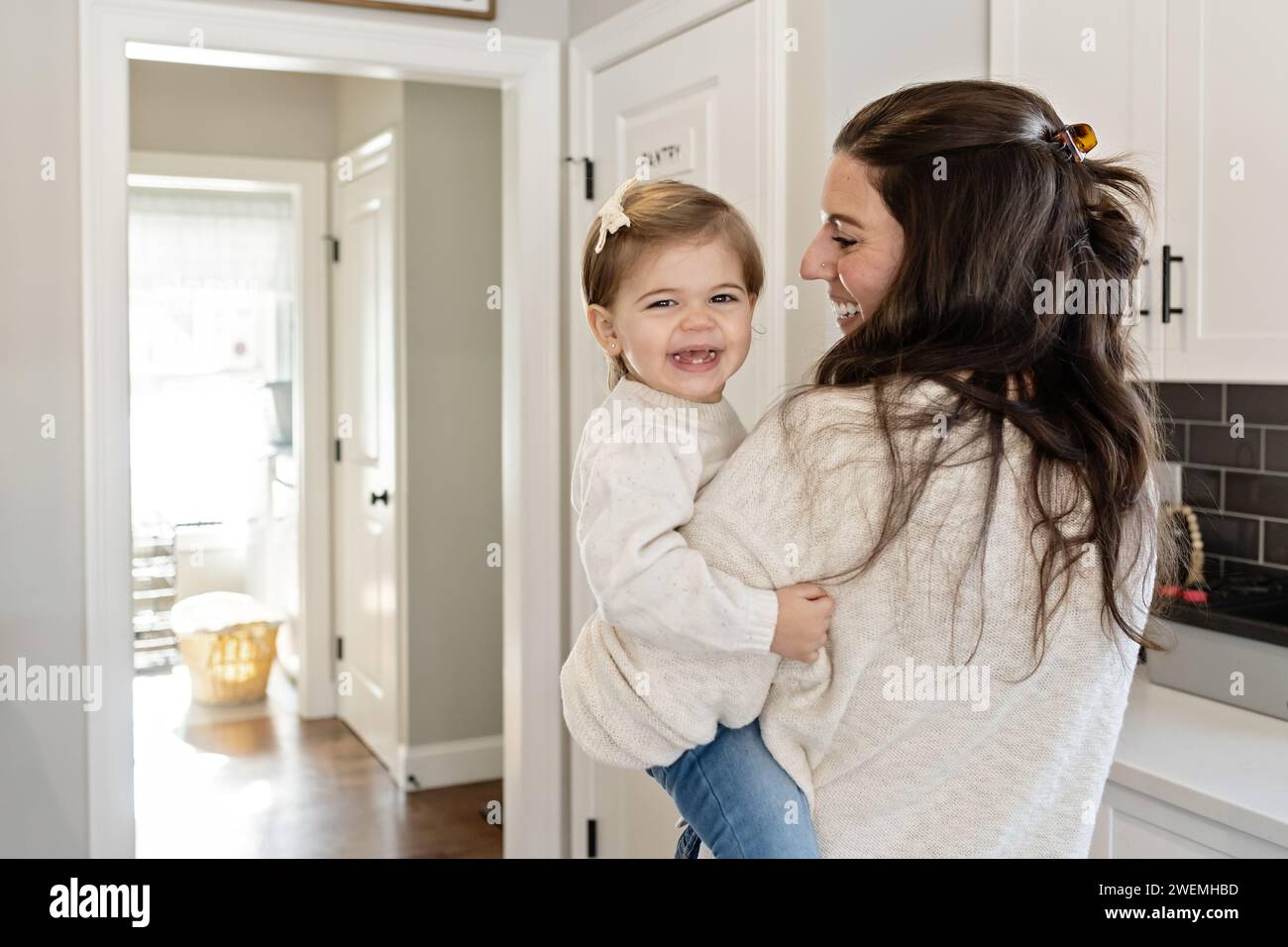 Jeune fille souriant et riant pendant que maman la regarde Banque D'Images