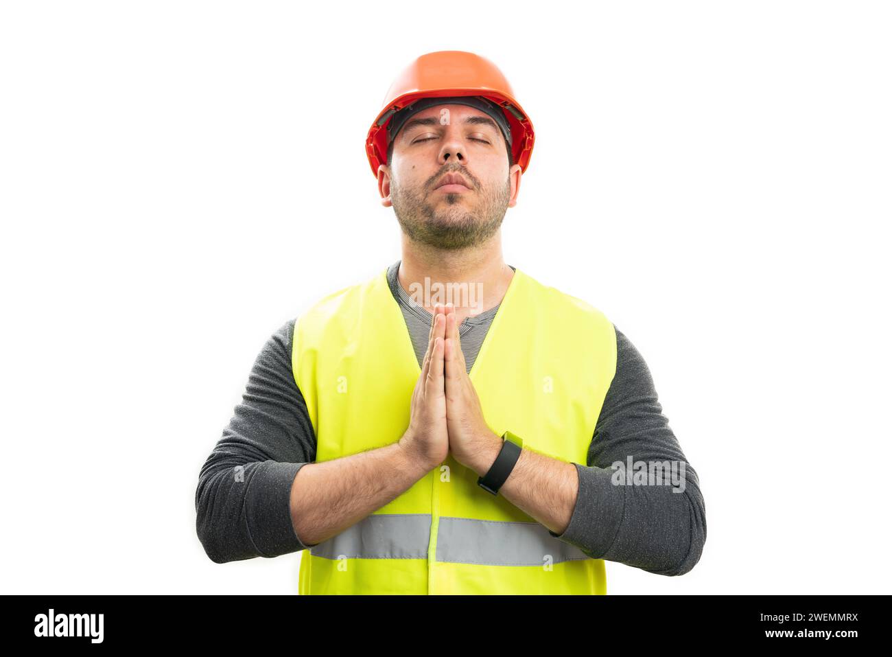 Constructeur masculin adulte tenant les mains ensemble comme geste de prière fidèle concept de croyant avec les yeux fermés isolé sur fond de studio blanc Banque D'Images