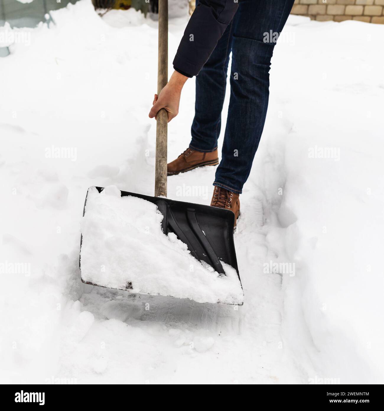 Un homme déneige les chemins sur sa propriété avec une pelle Banque D'Images