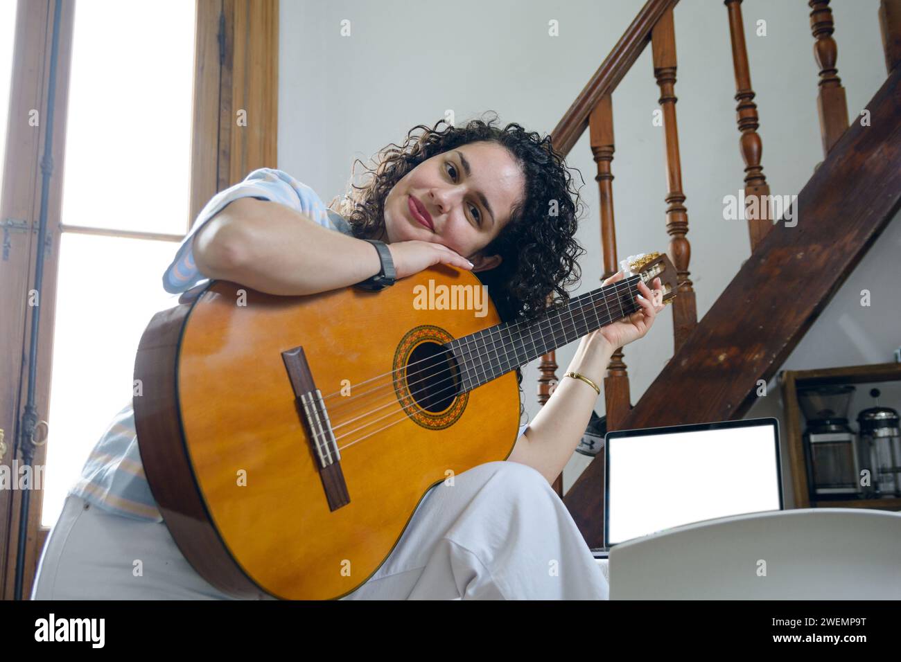 portrait de jeune femme latine en bigoudis et vêtements blancs guitariste debout à la maison appuyé sur sa guitare regardant la caméra et souriant, avec échelle Banque D'Images portrait de jeune femme latine en bigoudis et vêtements blancs guitariste debout à la maison appuyé sur sa guitare regardant la caméra et souriant, avec échelle Banque D'Images