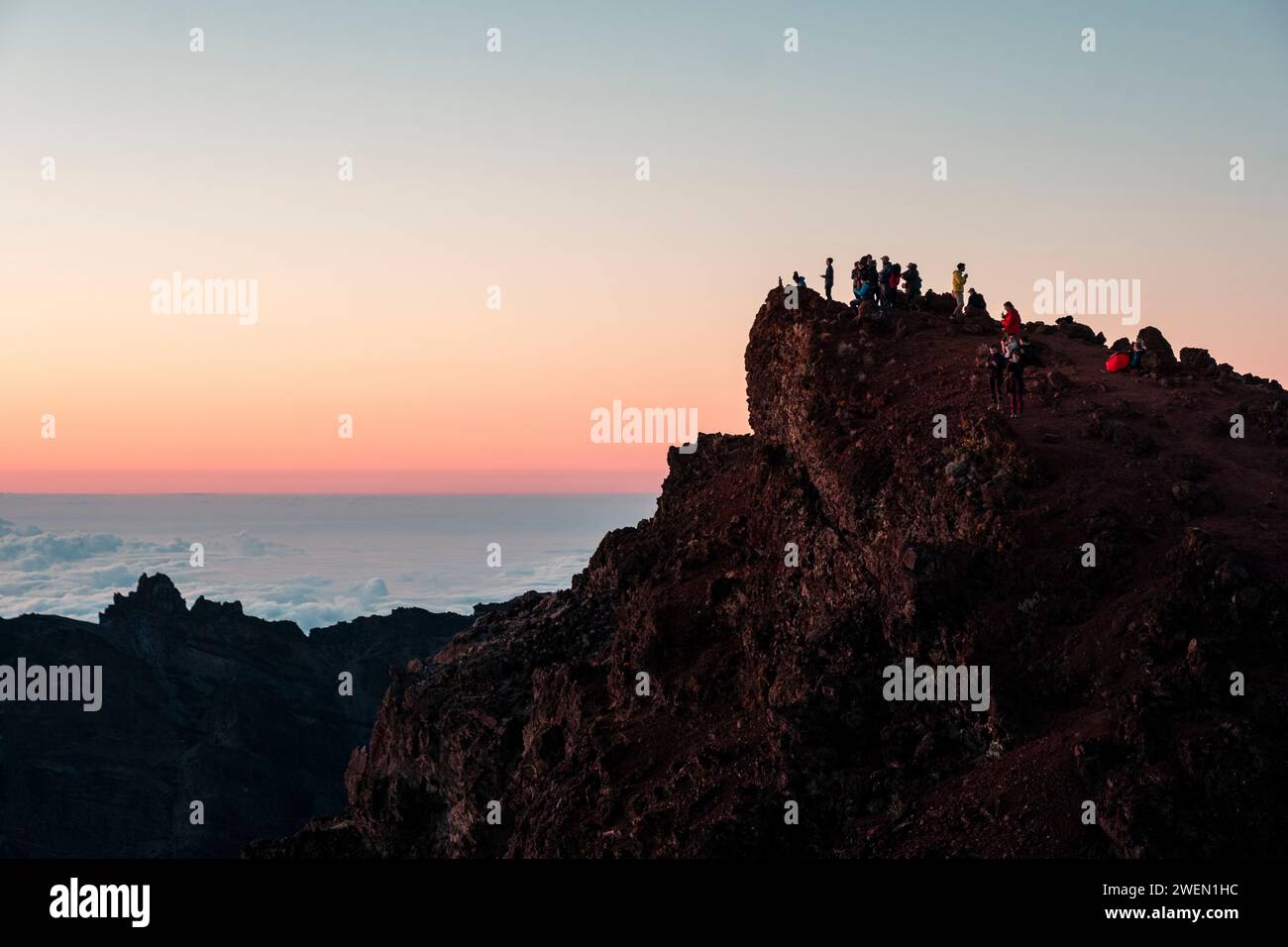 Un groupe de randonneurs se dresse au sommet du terrain accidenté du Piton des Neiges, témoin du lever du soleil à couper le souffle qui recouvre l'île de la Réunion de teintes chaudes Banque D'Images