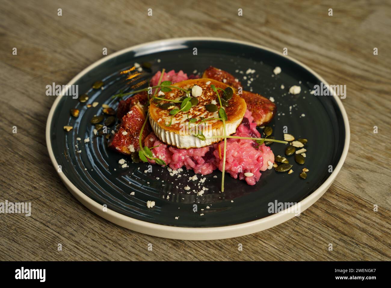 Risotto à la betterave, fromage de chèvre grillé, figue et graines de citrouille grillées sur table en bois Banque D'Images