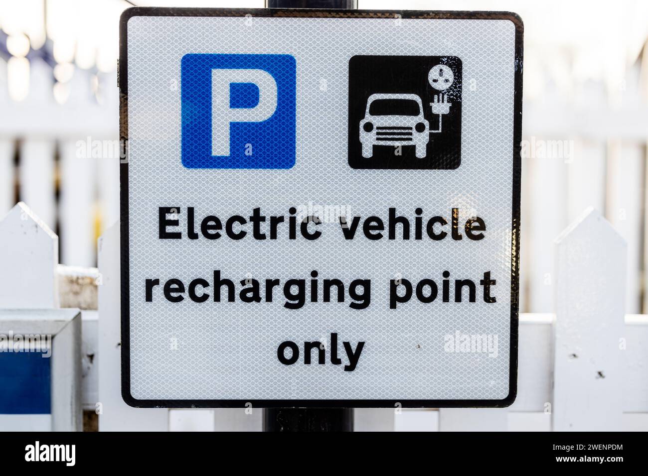 gros plan d'une borne de recharge et d'un panneau de stationnement. Le panneau est monté près d'une clôture et affiche le texte point de charge du véhicule électrique uniquement. Banque D'Images