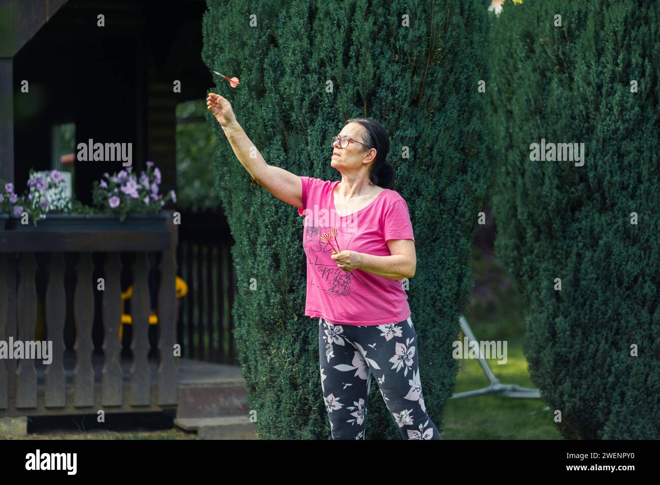 Une femme âgée jouant aux fléchettes dans le jardin. Elle est en plein air un jour d'été Banque D'Images