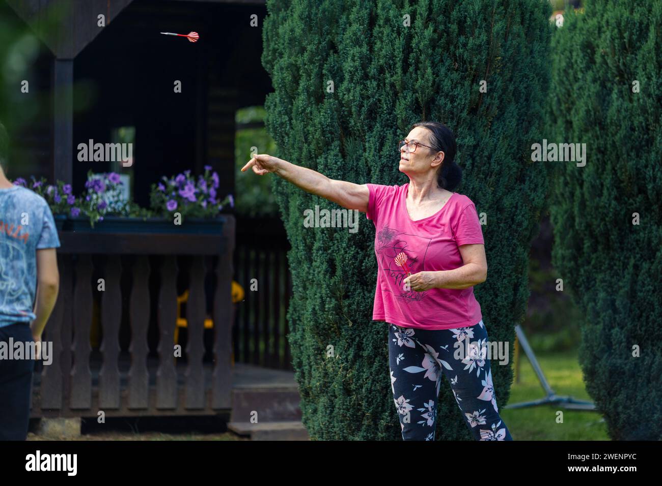 Une femme âgée jouant aux fléchettes dans le jardin. Elle est en plein air un jour d'été Banque D'Images