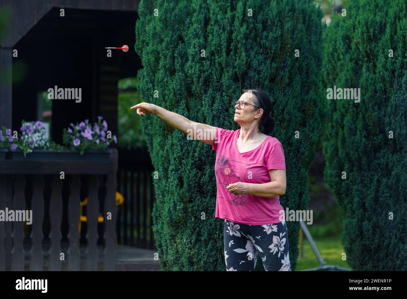 Une femme âgée jouant aux fléchettes dans le jardin. Elle est en plein air un jour d'été Banque D'Images