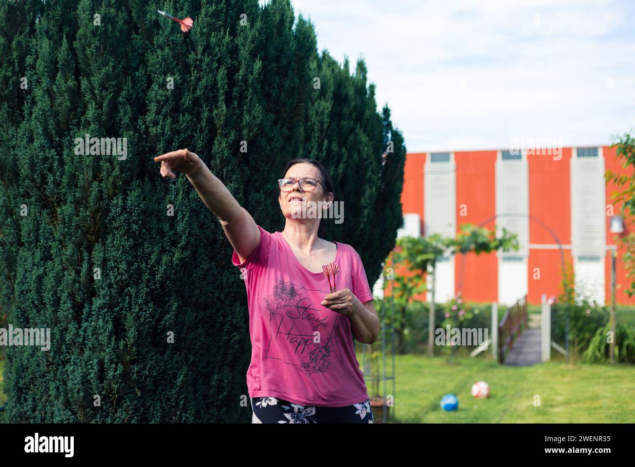 Une femme âgée jouant aux fléchettes dans le jardin. Elle est en plein air un jour d'été Banque D'Images
