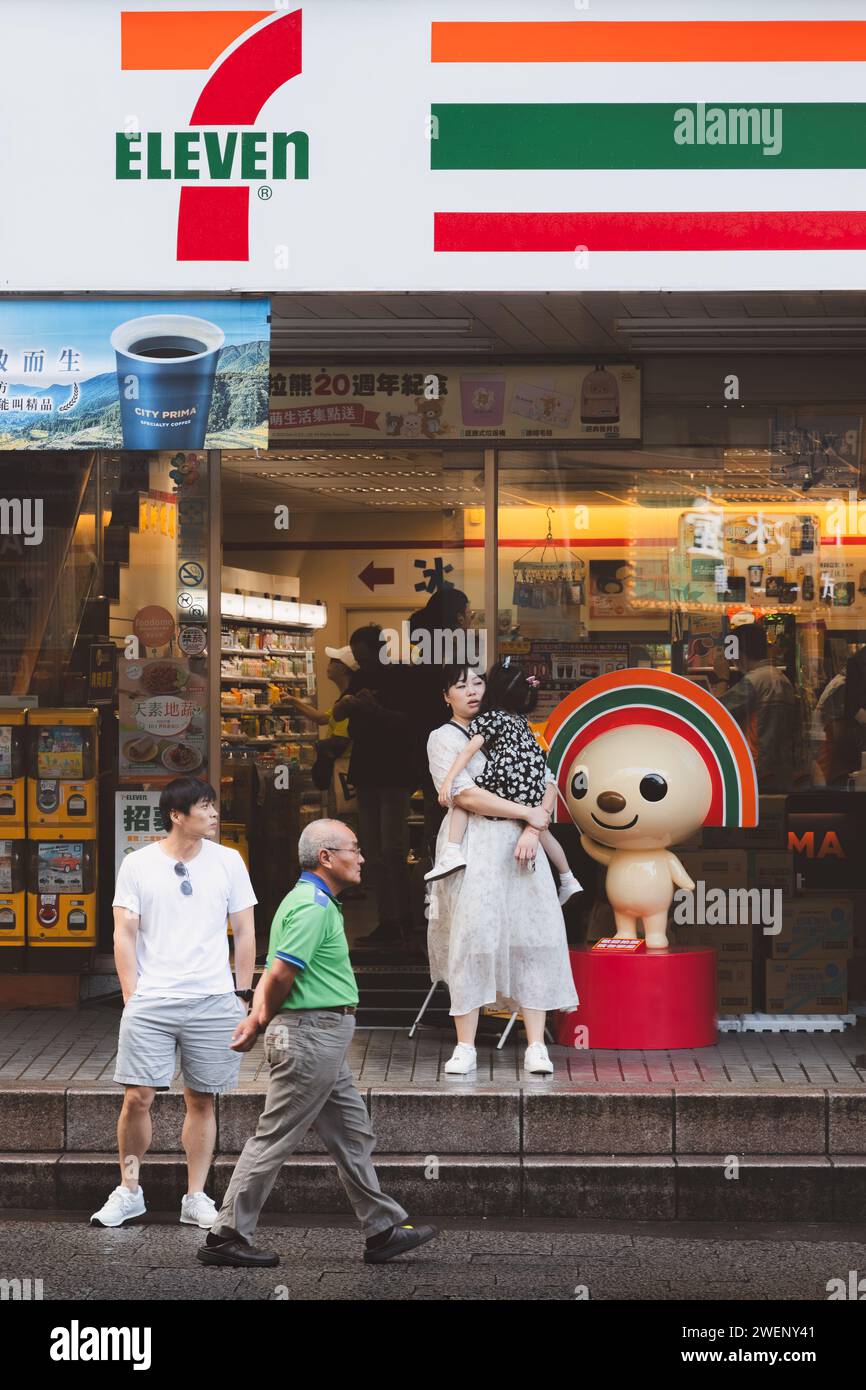 Taipei, Taiwan - 1 octobre 2023 : des citadins animés et colorés et des scènes de rue devant le dépanneur 7-11 et la mascotte Open-Chan dans le bustli Banque D'Images