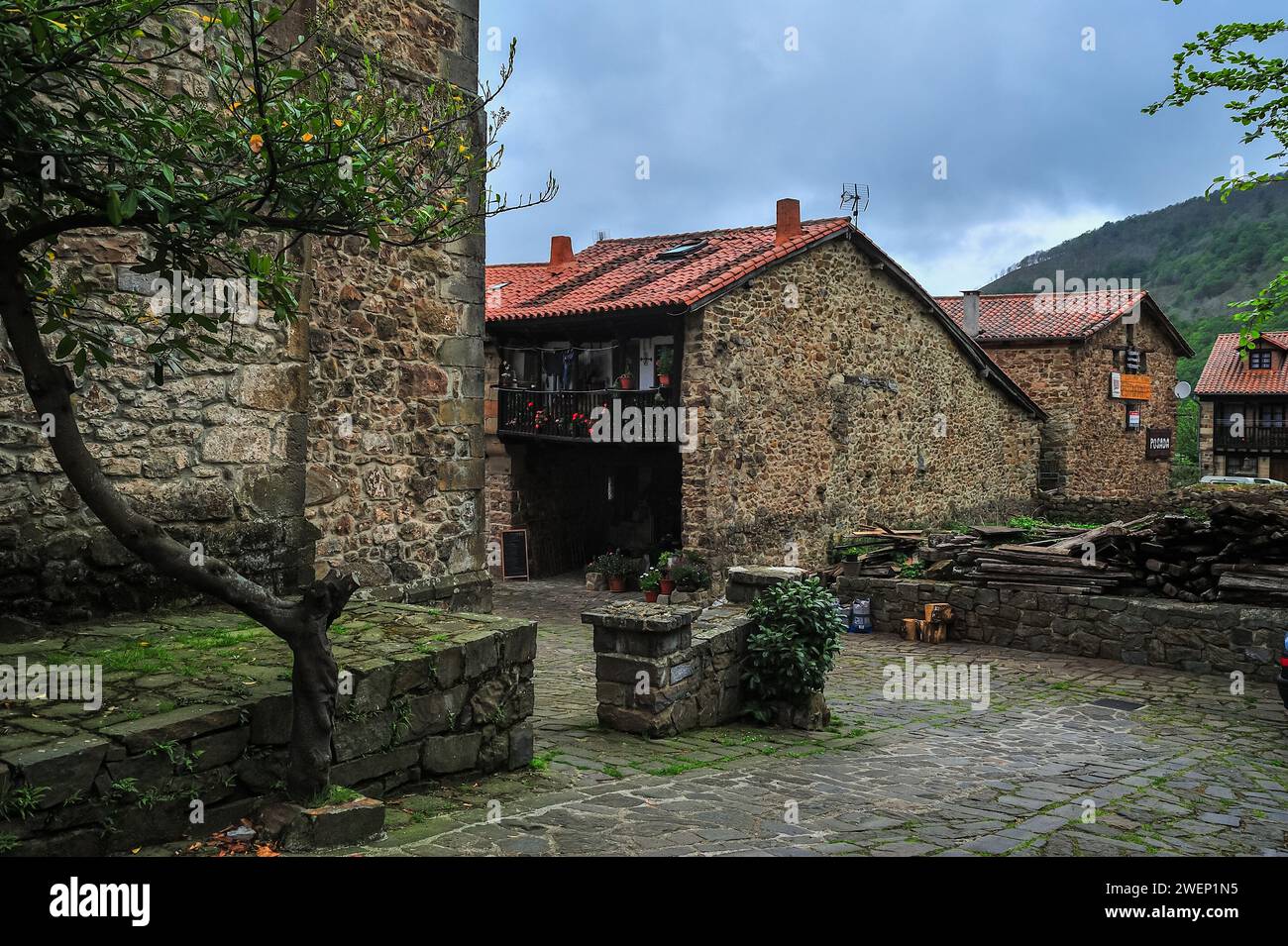 Un chemin serein bordé de pavés flanqué de maisons traditionnelles en pierre et de verdure luxuriante dans un village européen pittoresque Banque D'Images