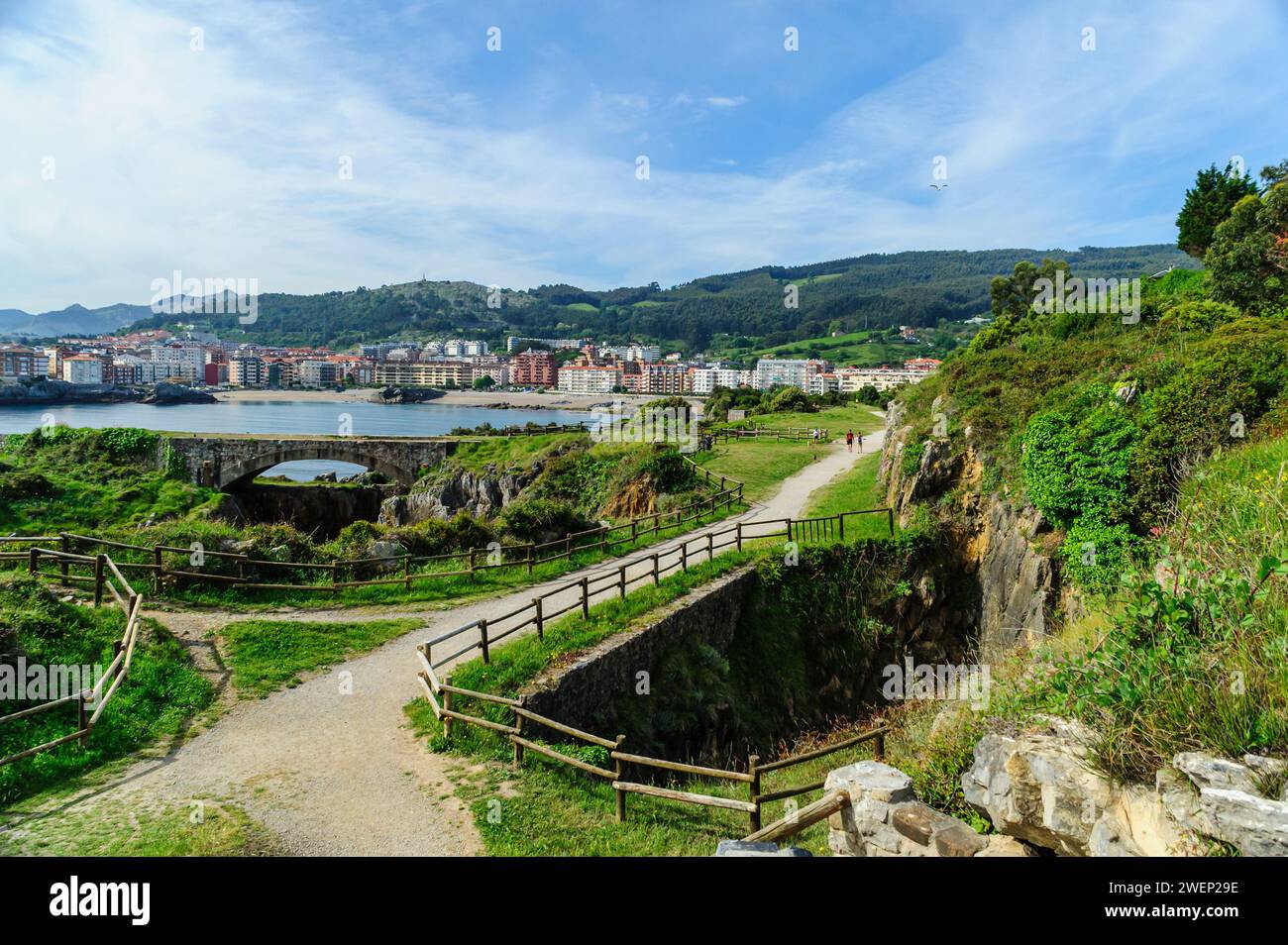 Un sentier de randonnée pittoresque le long de la côte rocheuse avec vue sur la ville de Castro Urdiales et les collines luxuriantes en arrière-plan. Banque D'Images