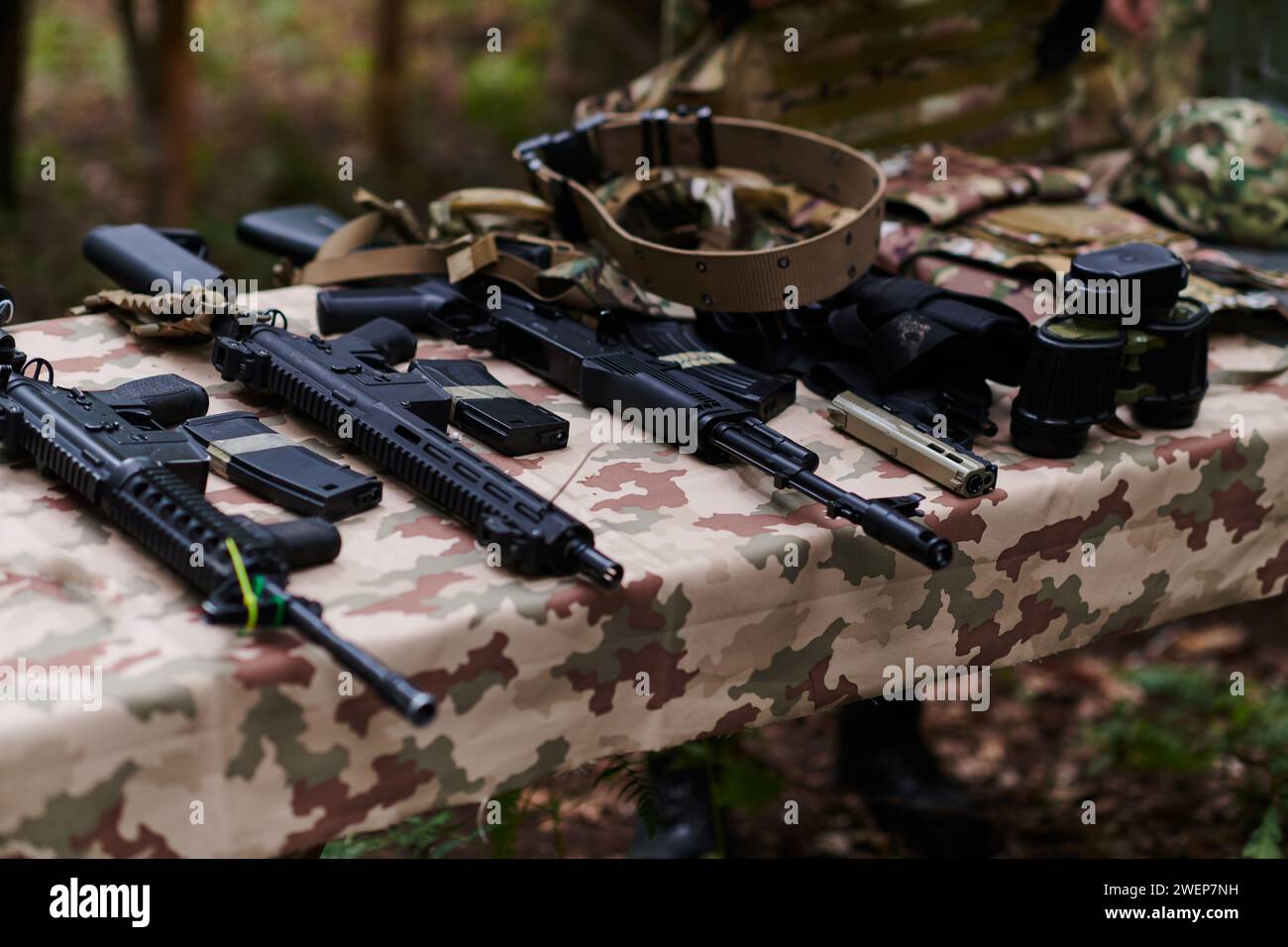 Un ensemble d'armes militaires, y compris des fusils et des pistolets, est méticuleusement disposé sur une table dans une base militaire, présentant une vue rapprochée du Banque D'Images