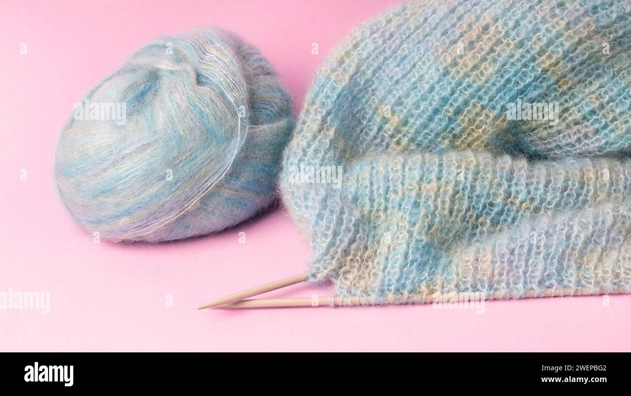 Boules de fil colorées et aiguilles à tricoter isolées sur rose Banque D'Images