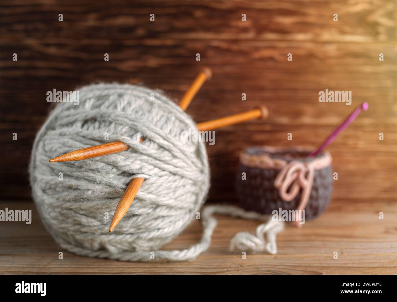 Les aiguilles à tricoter en bois sortent des écheveaux de fil sur un fond en bois. Banque D'Images