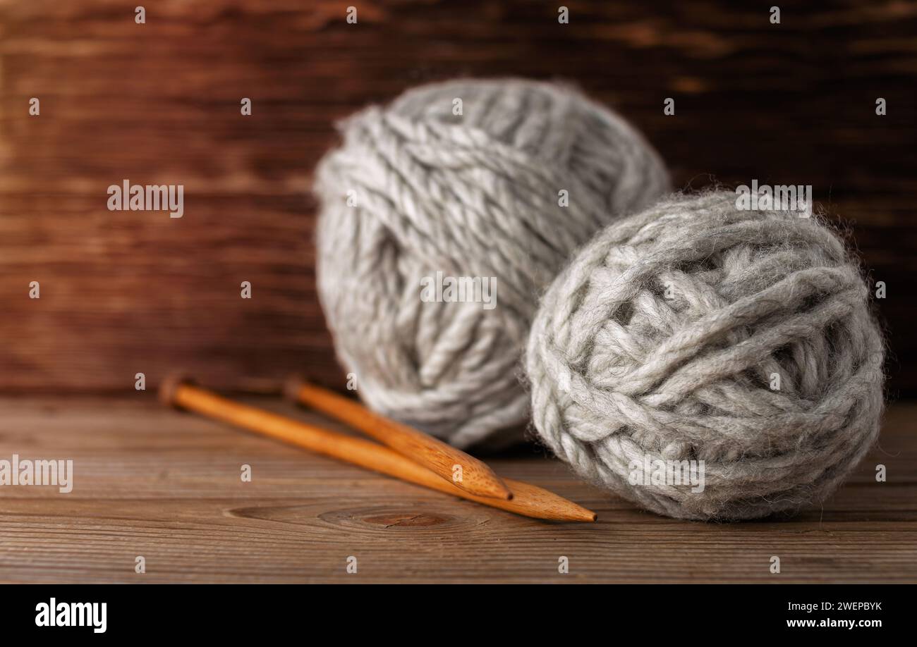 Boules d'aiguilles à tricoter en fil de laine sur un fond en bois. Accessoires de tricotage. Banque D'Images