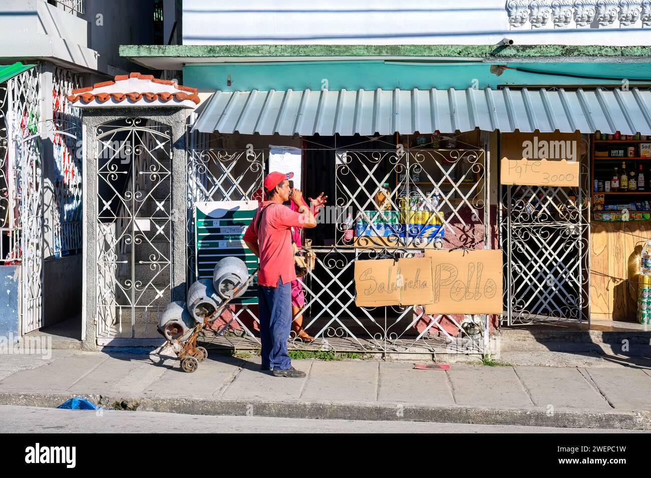 Homme avec des réservoirs de gaz naturel devant une petite entreprise alimentaire, Cuba Banque D'Images