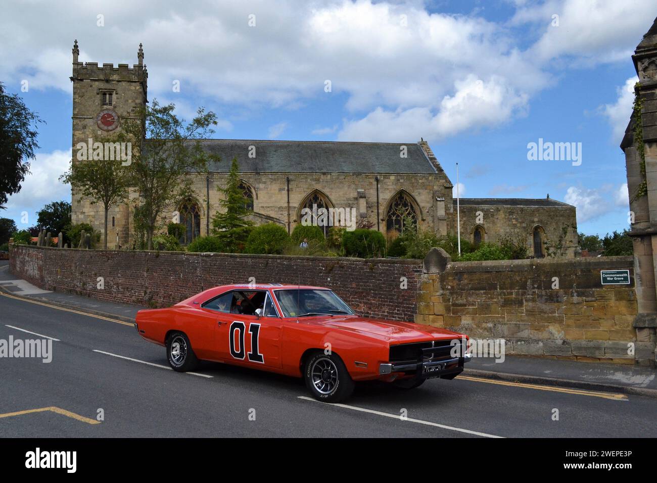Réplique 01 Dukes of Hazzard voiture américaine passant devant All Saints Church dans Hunmanby Village North Yorkshire - Royaume-Uni Banque D'Images