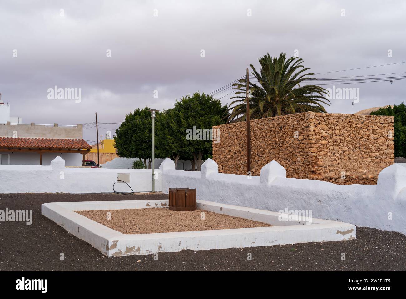 Une scène tranquille sur le terrain Ermita de San Marcos à Tiscamanita, présentant un jardin, des murs en pierre et des bâtiments environnants sous un ciel nuageux. Banque D'Images