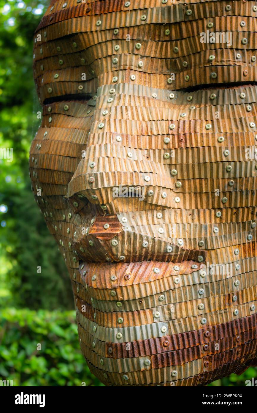 Une sculpture de visage en bois avec des yeux rivetés Banque D'Images