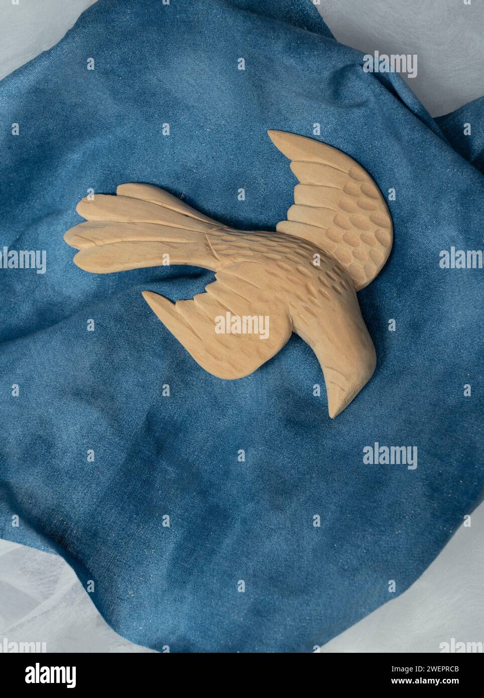 Grand oiseau sculpté de figure de colombe sur le tissu bleu semble descendre en vol. Les ailes sont déployées comme si elles venaient chercher la paix et l'amour. Banque D'Images