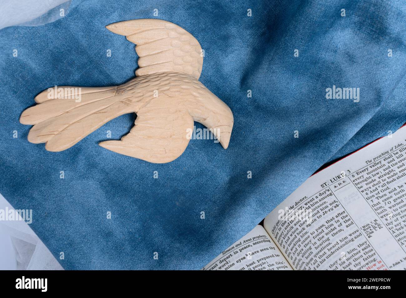 La figure du Saint-Esprit descend sur la lecture ouverte de la Bible de Saint Luc. La colombe est une sculpture en bois vue avec un fond bleu de tissu représentant le ciel. Banque D'Images