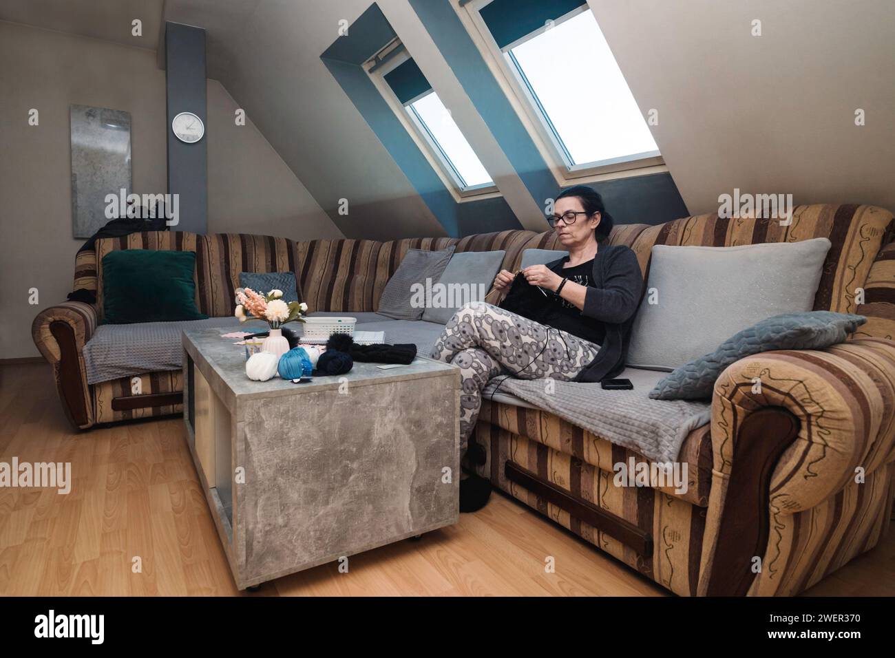 Une femme âgée assise dans son salon et tricotant avec de la laine Banque D'Images