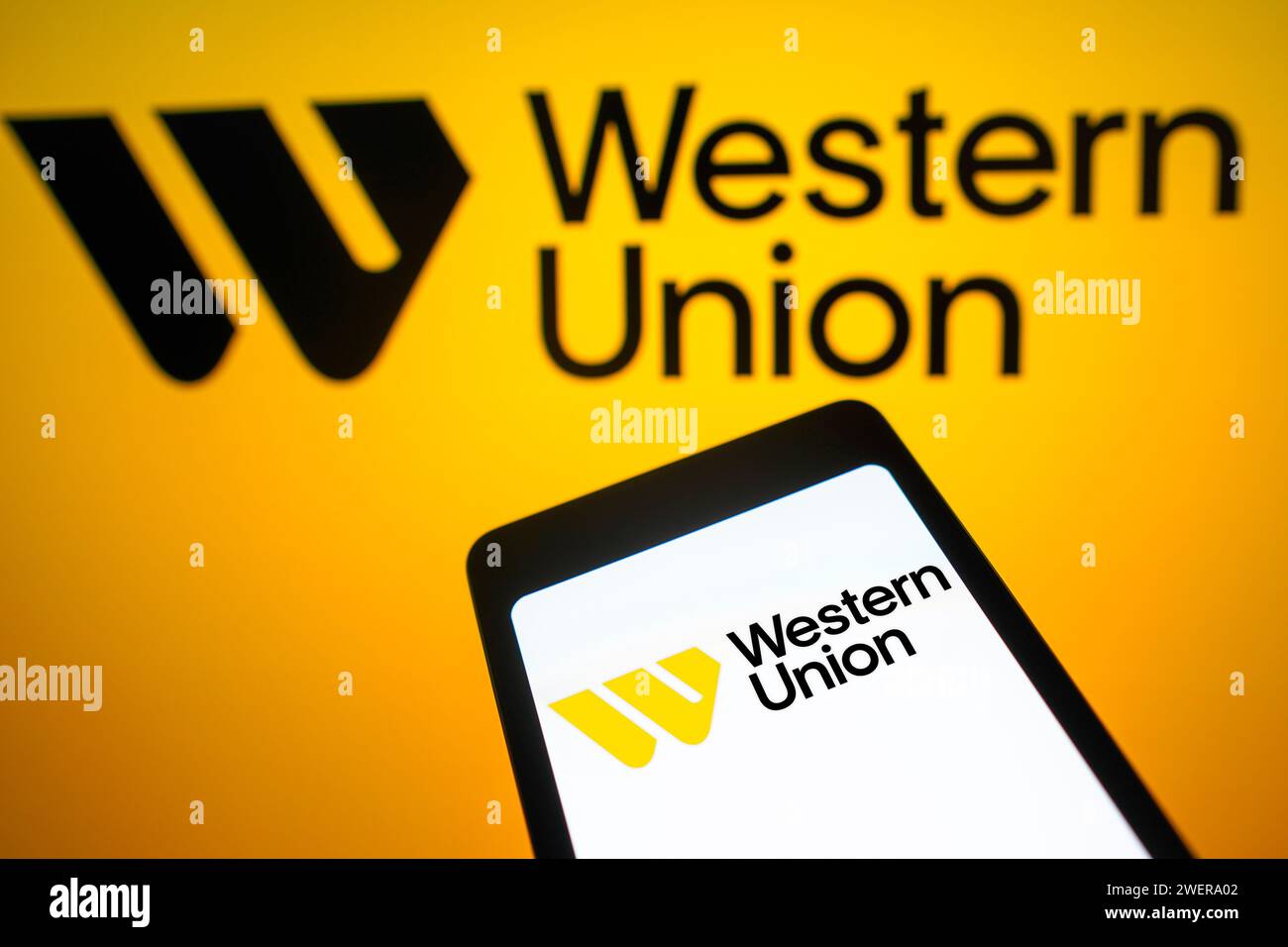 Sur cette photo, le logo Western Union est affiché sur l'écran d'un smartphone et en arrière-plan. Banque D'Images