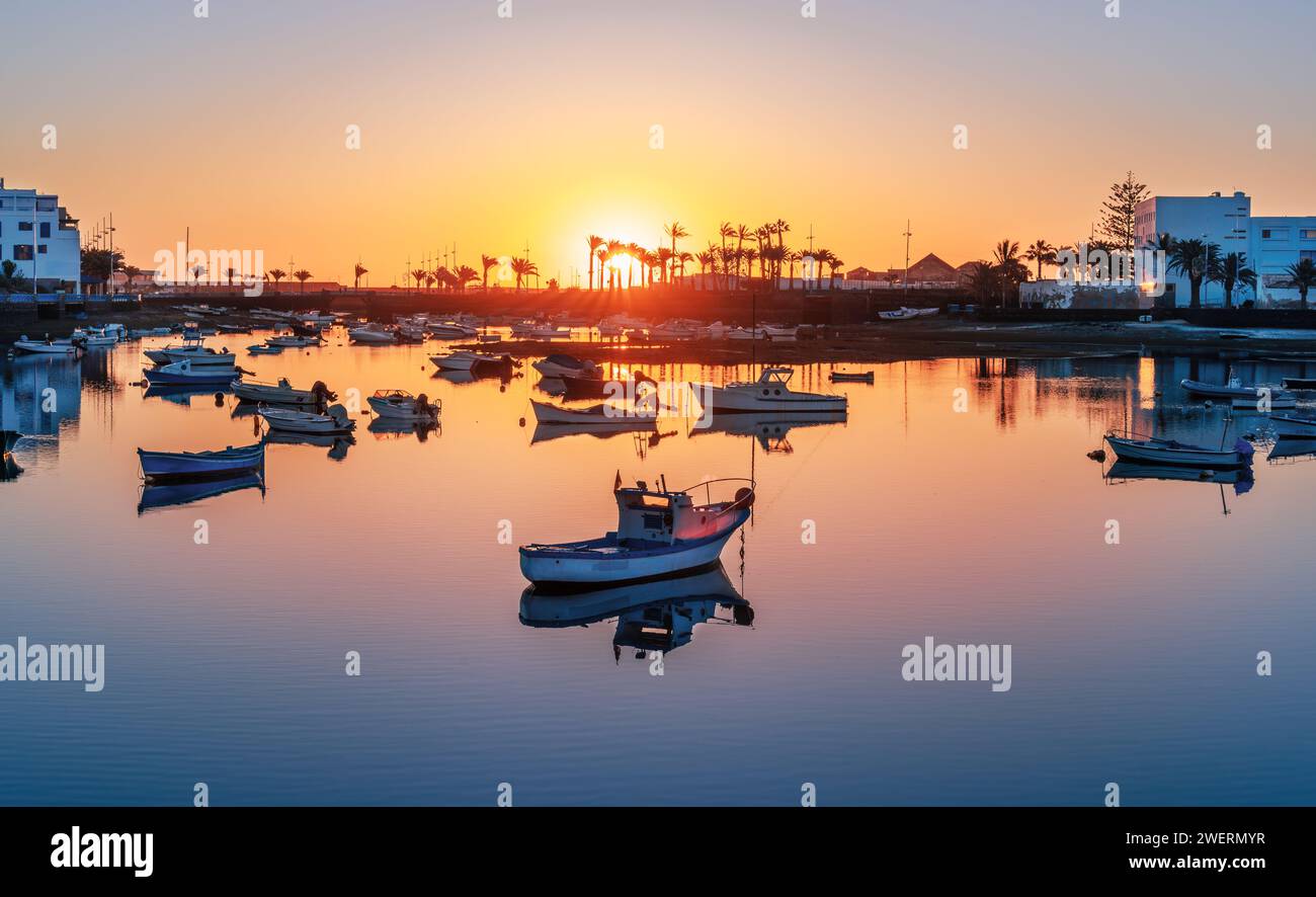 Lever de soleil Lanzarote sur Arrecife avec un bateau solitaire sur des eaux calmes. La côte de la capitale créant une scène tranquille sur le lac Charco de San Gines. Banque D'Images