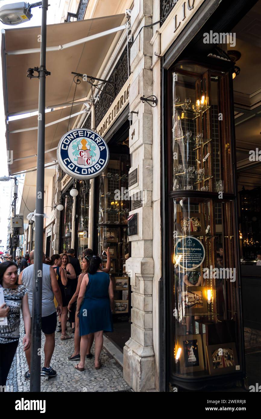 Panneau rond suspendu à l'entrée du café Confeitaria Colombo situé à Goncalves Dias rue dans le quartier Centro tandis que les piétons passent. Banque D'Images