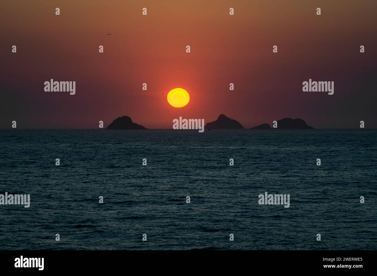 Coucher de soleil rouge crépuscule vue du ciel vu de la roche Arpoador (Pedra do Arpoador) avec les îles Tijucas en vue à l'horizon sous le ciel ensoleillé de l'après-midi d'été. Banque D'Images