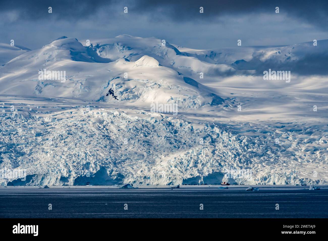 Un bateau de croisière nain par un glacier géant près de la péninsule antarctique, Antarctique. Banque D'Images