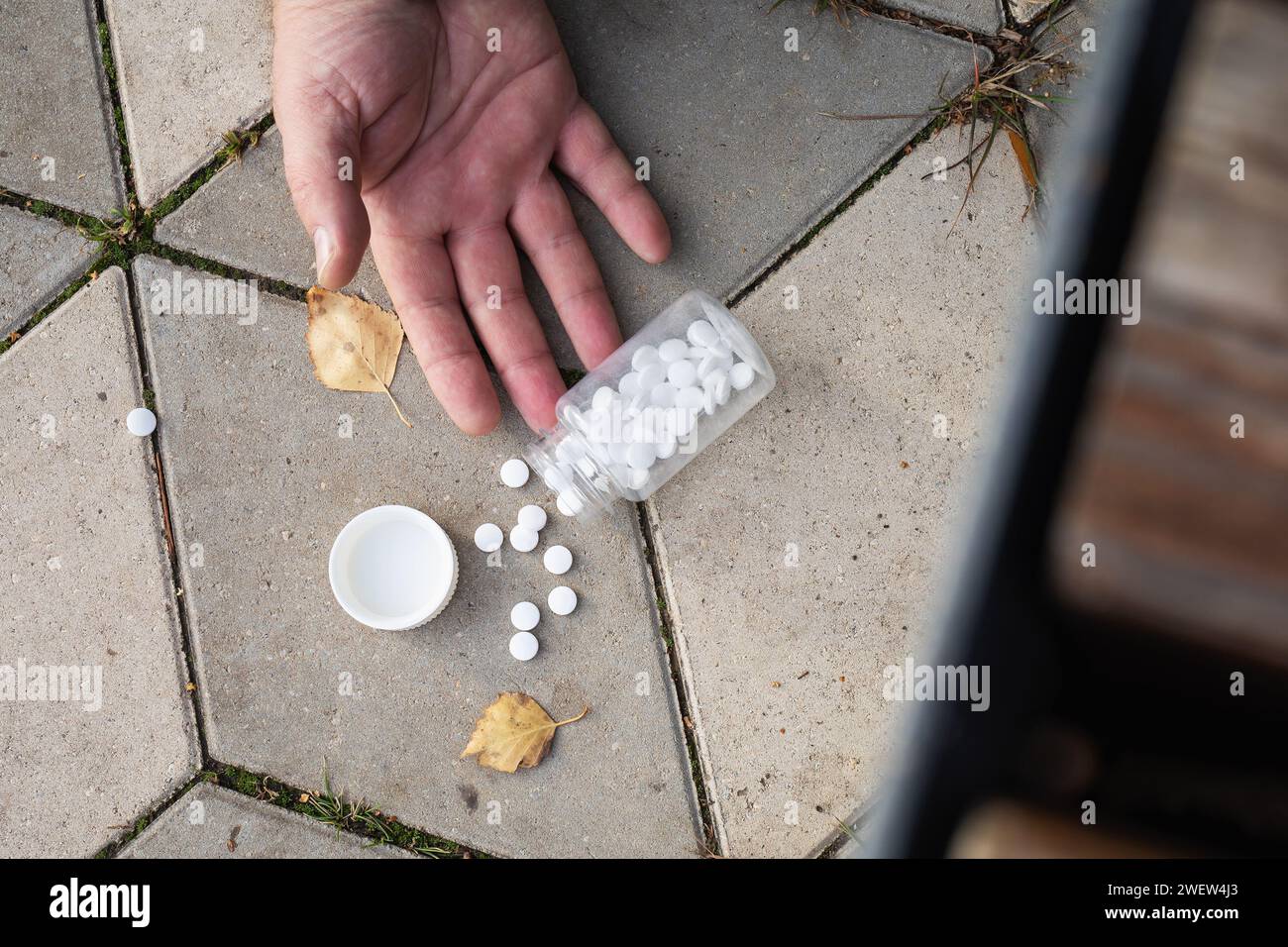 Pilules tombant des mains au sol, concept sur le thème d'une forte détérioration de la santé dans la rue Banque D'Images