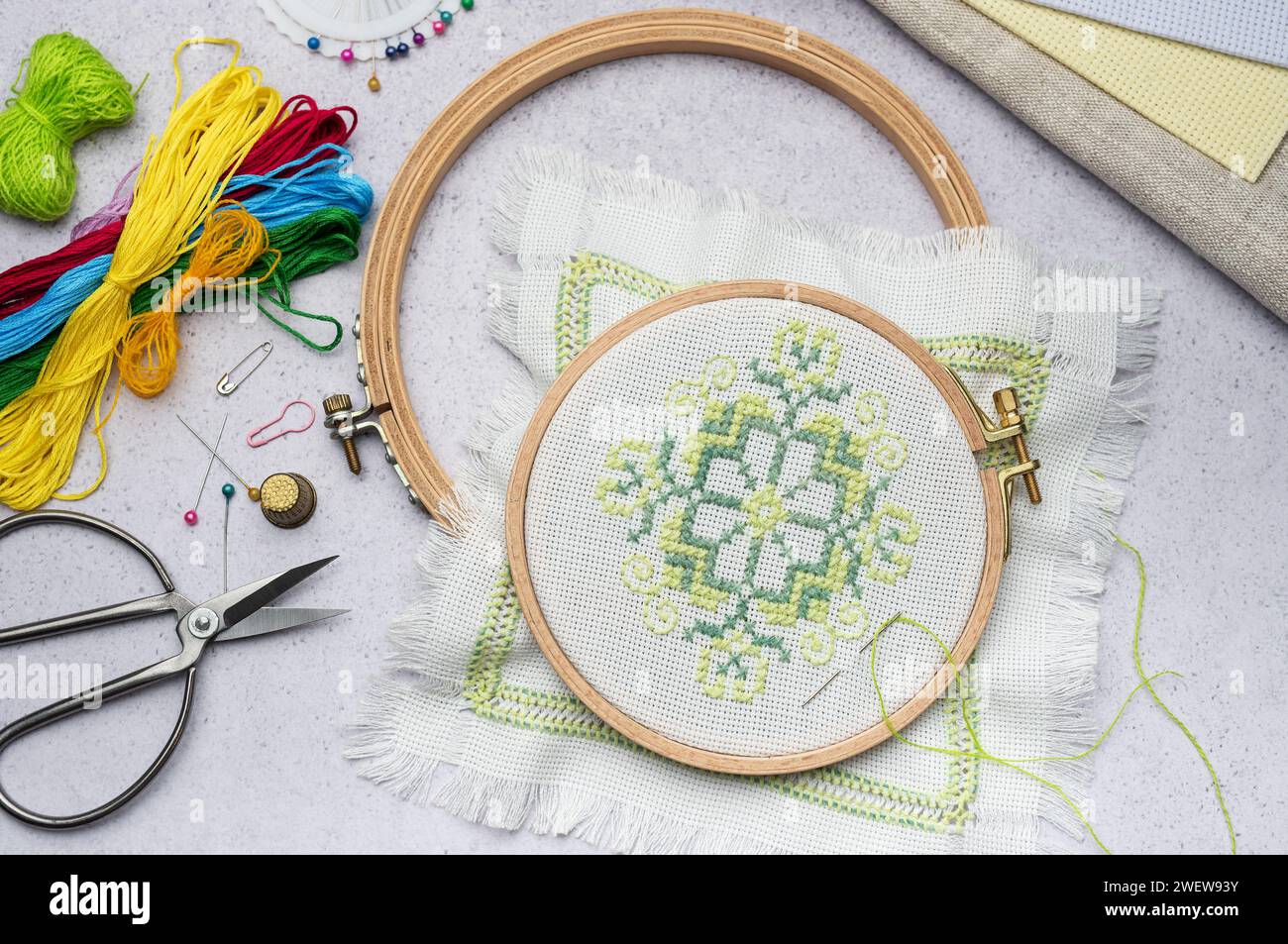 Broderie avec des fils colorés et divers accessoires de couture sur la table Banque D'Images