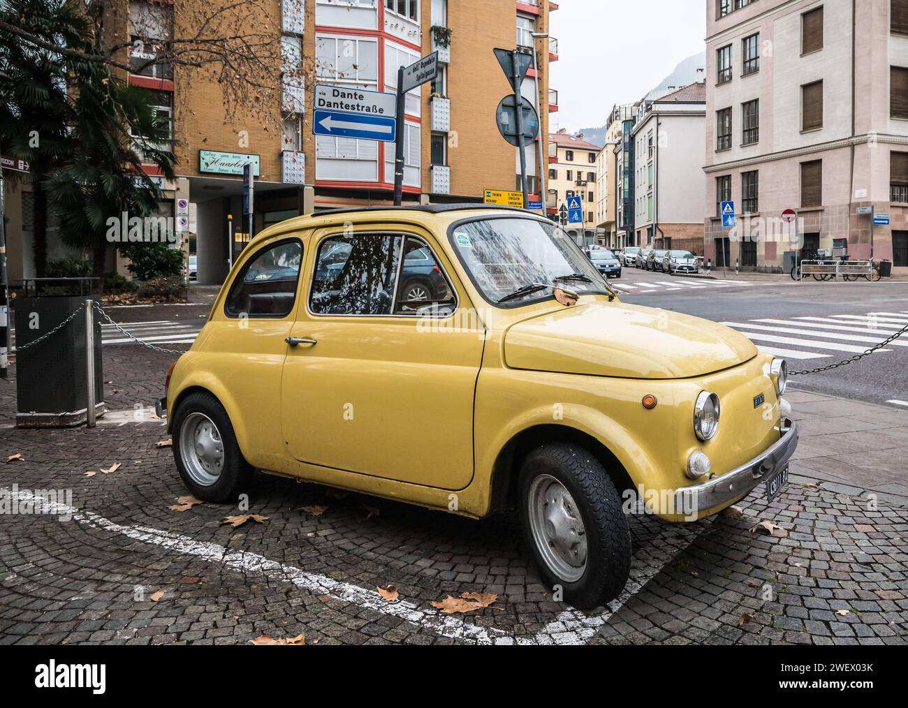 Vieille voiture classique jaune rétro Fiat 500 sur la rue de la ville de Bolzano dans le Tyrol du Sud, Trentin Haut-Adige, Italie du Nord, Europe. Banque D'Images