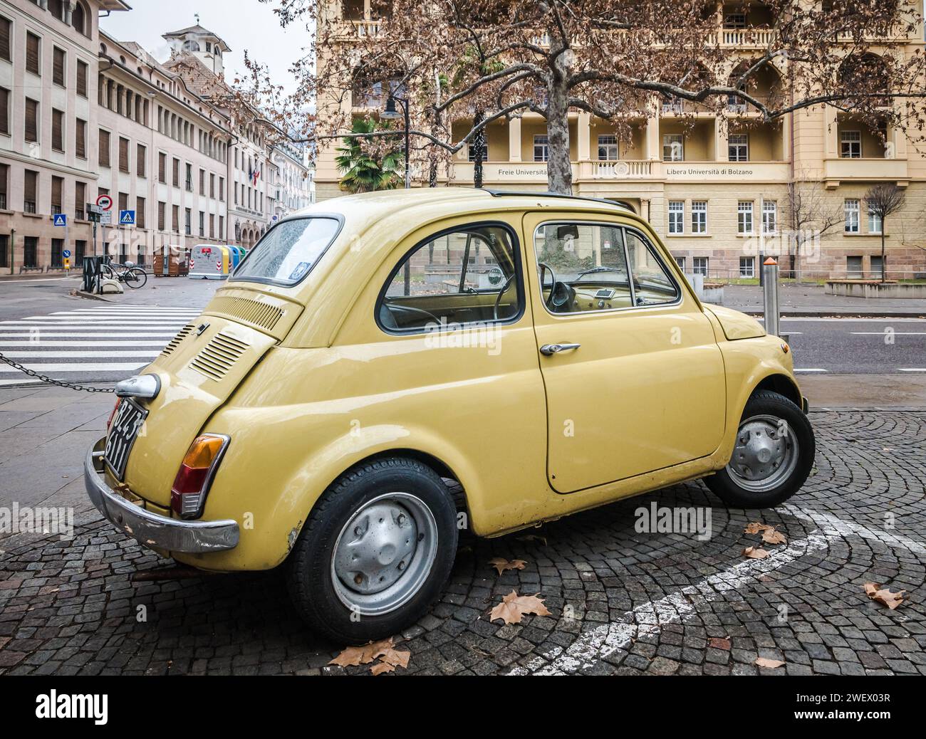 Vieille voiture classique jaune rétro Fiat 500 sur la rue de la ville de Bolzano dans le Tyrol du Sud, Trentin Haut-Adige, Italie du Nord, Europe. Banque D'Images